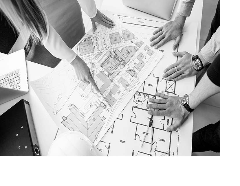 Hands reviewing architectural plans on a table during a design meeting.
