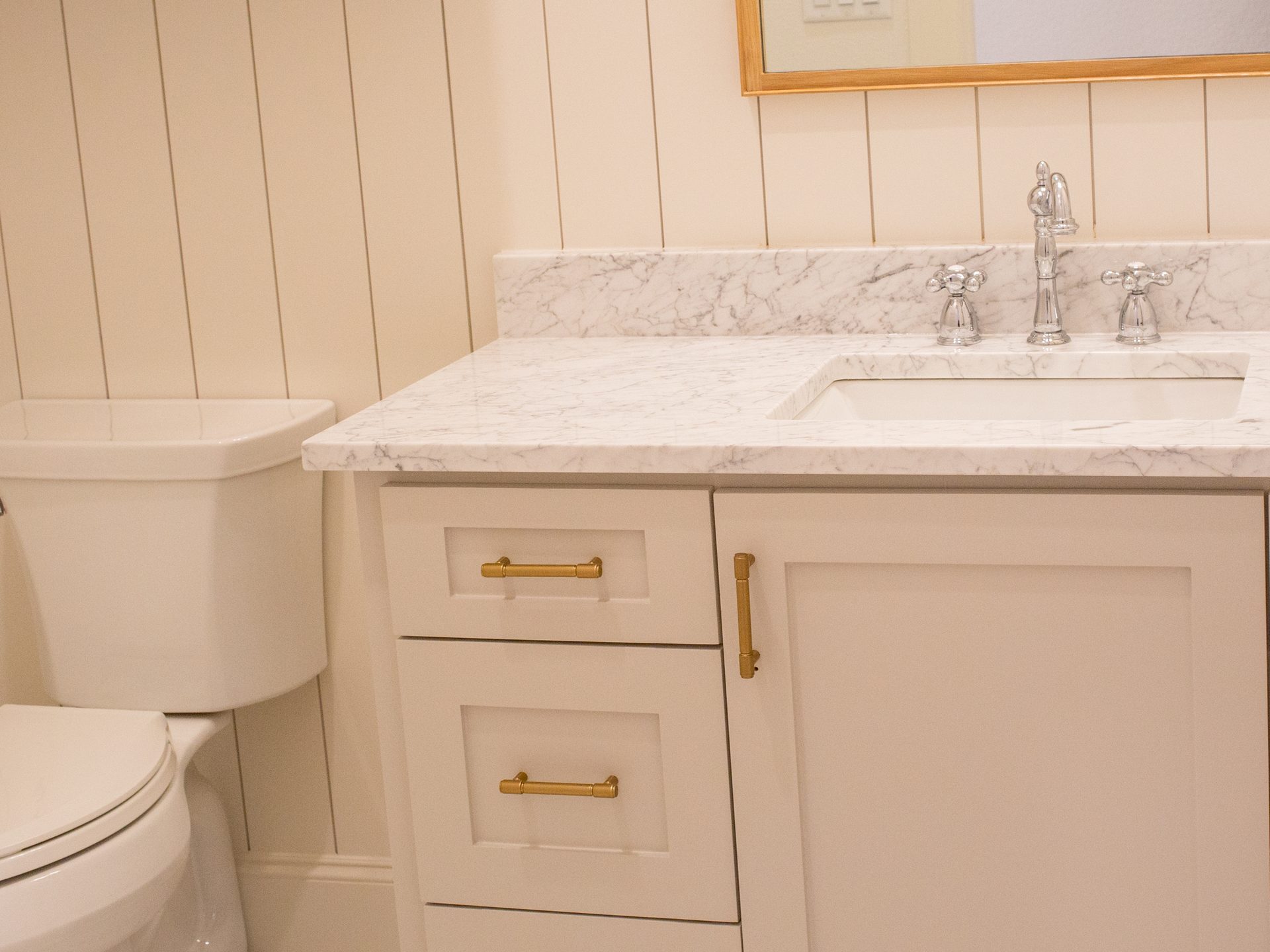 Primary bath vanity with marble counter, brass hardware, and chrome faucet.