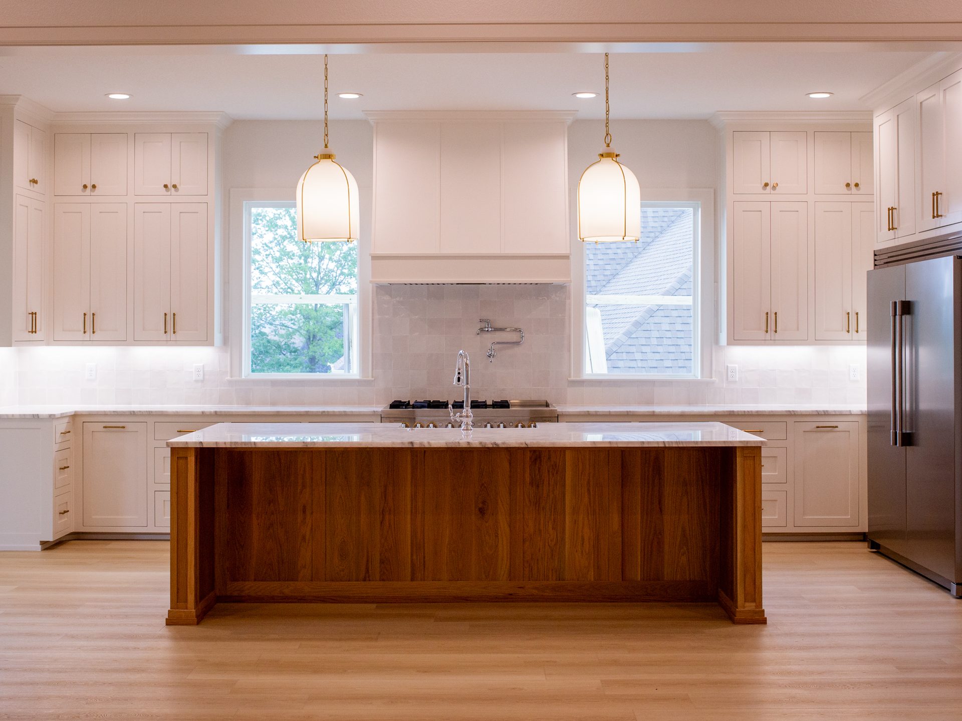Brass-and-glass pendants over a walnut kitchen island.