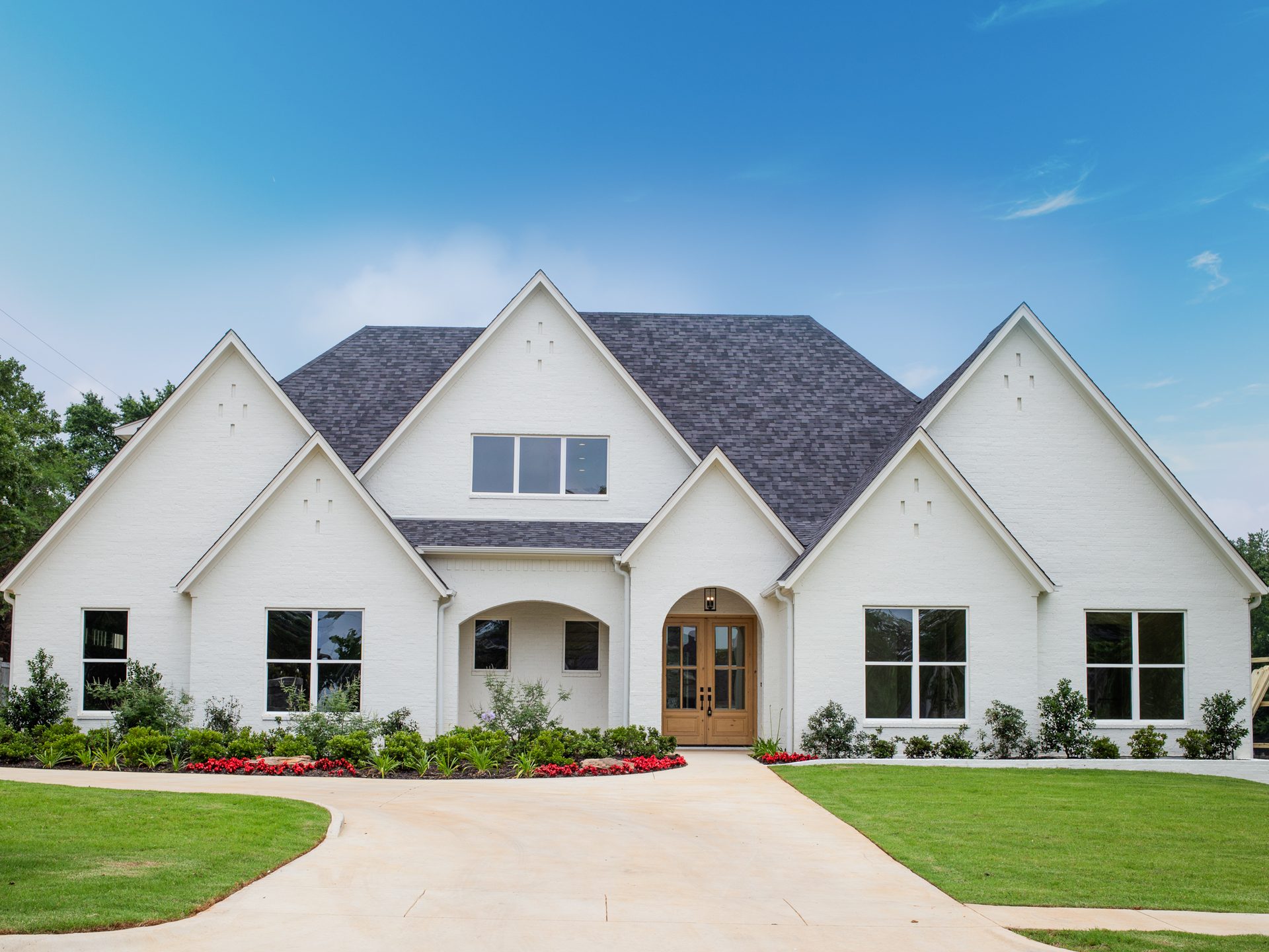 White brick Nicholas Humphrey home with steep gables and a wood arched entry.