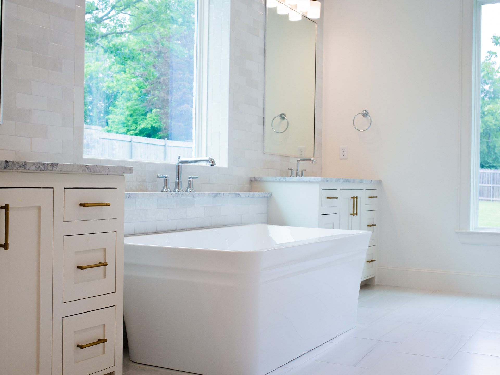 Primary bathroom with freestanding soaking tub and stone walls.