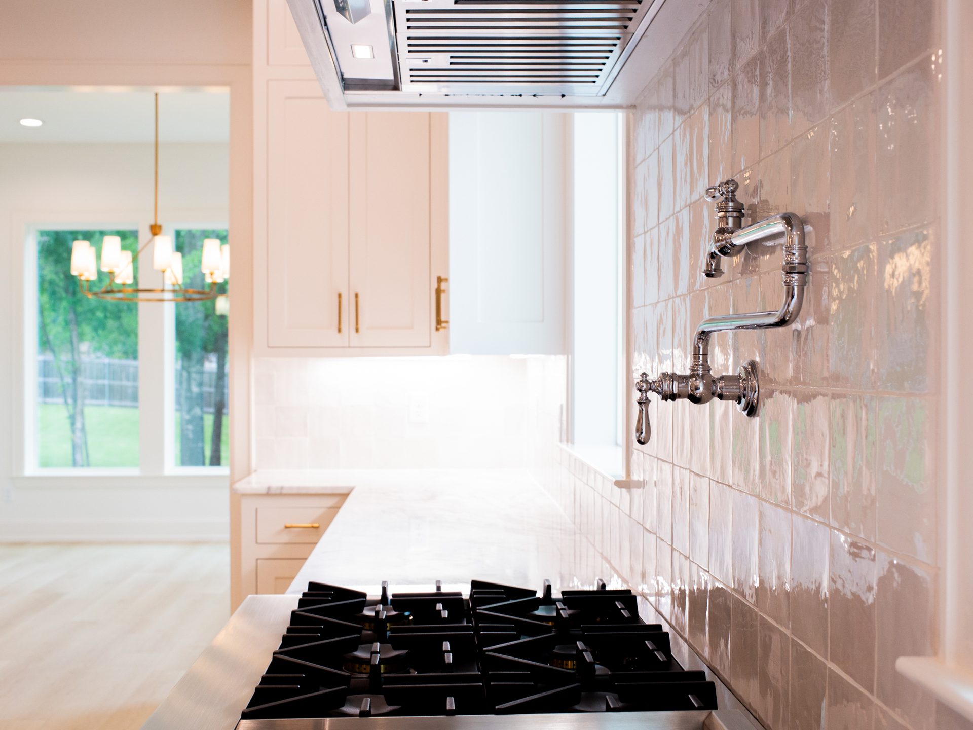 Cooktop with custom hood and marble backsplash in a Nicholas Humphrey kitchen.